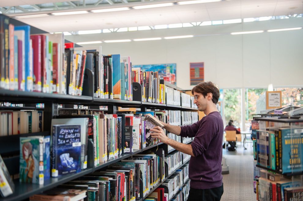 Person shelving books at Tommy Douglas Person shelving books at Tommy Douglas
